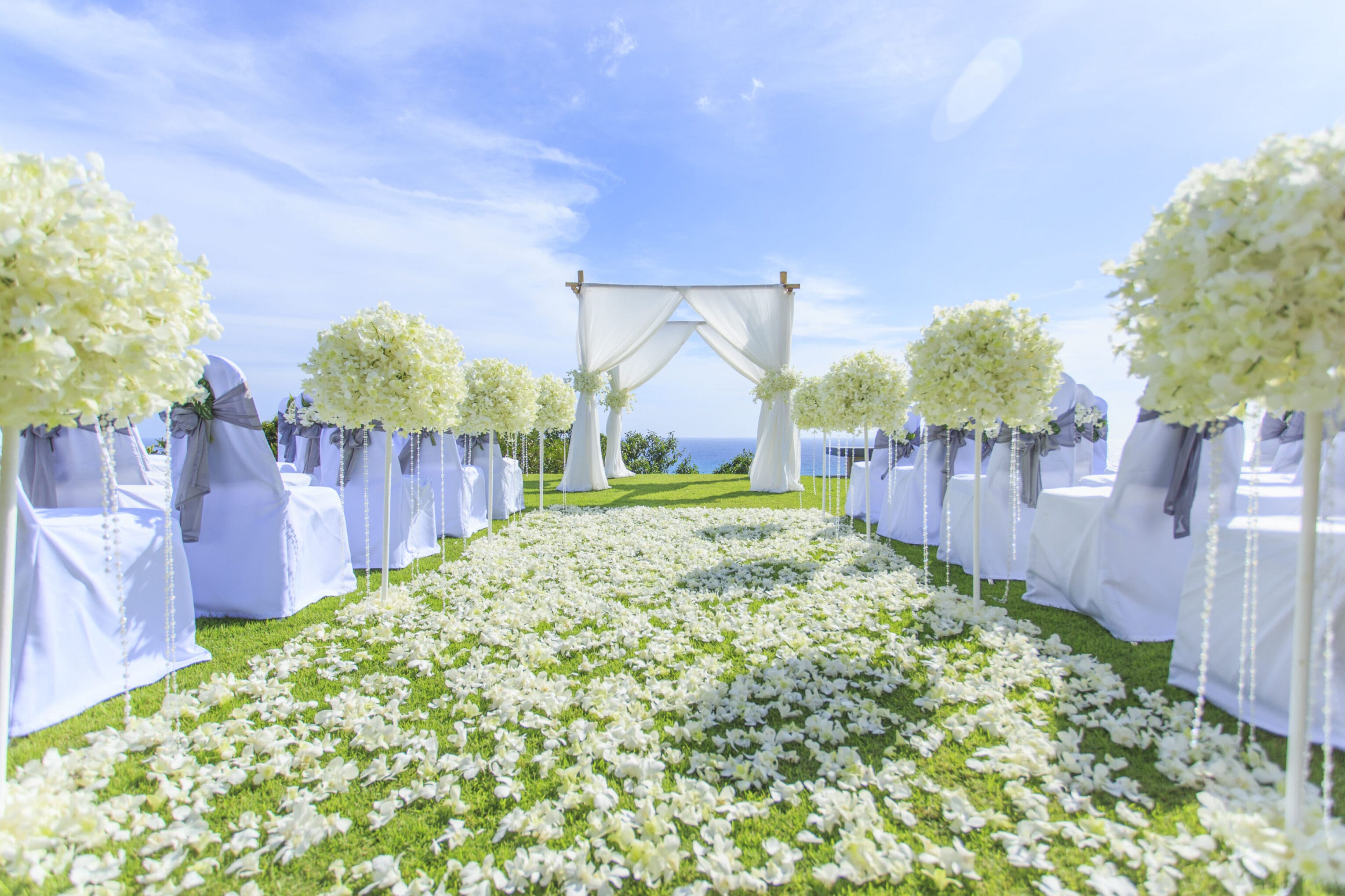 A wedding ceremony with white flowers and blue sky.