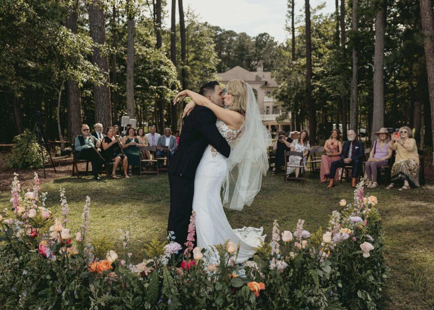 A bride and groom share a joyful embrace at their outdoor wedding ceremony.