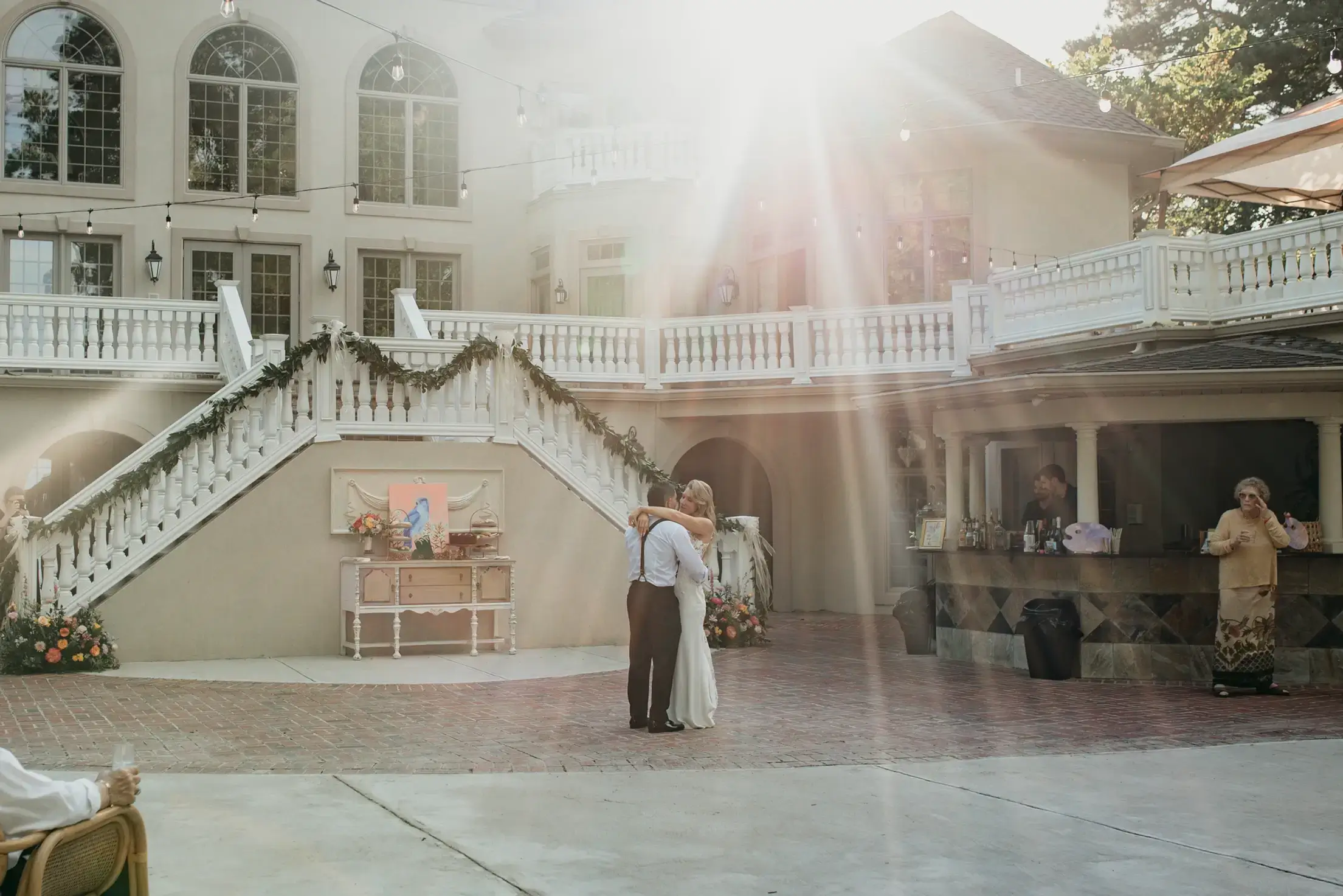 Couple dancing outside elegant building, sunlight streaming.