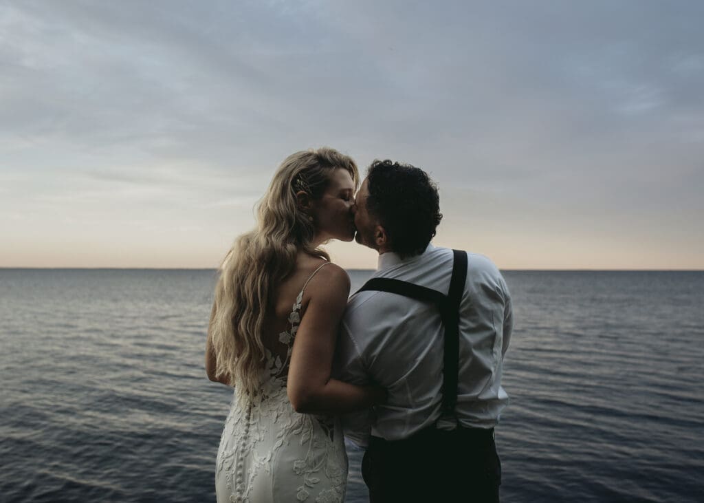 Bride and groom kissing by the sea
